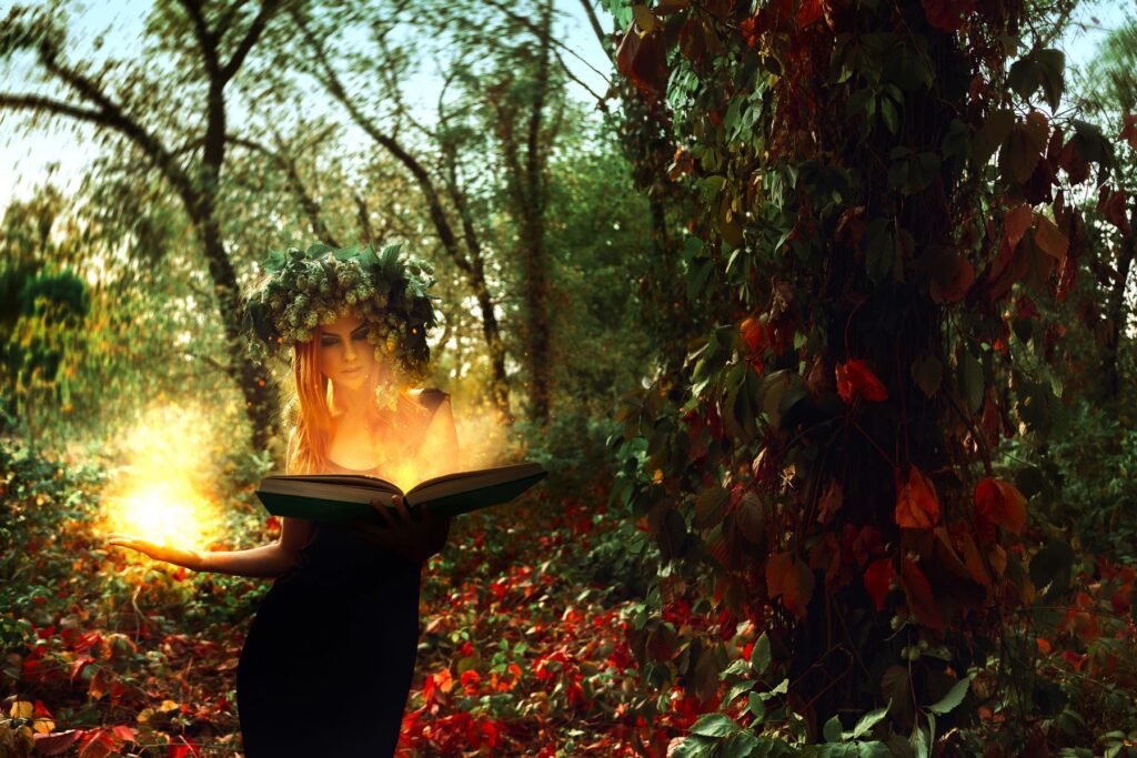 Young witch conjuring magick from her book of shadows, outdoors in the woods.